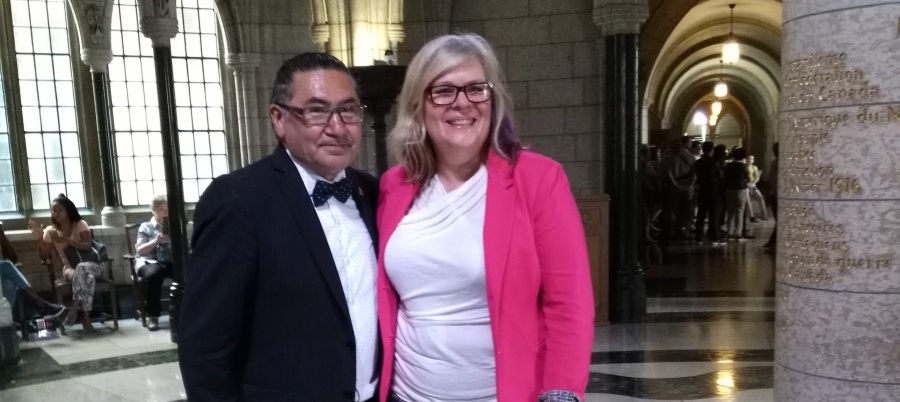 Romeo Saganash and Jennifer Preston pose in the House of Commons after Bill C-262 passes in the House.