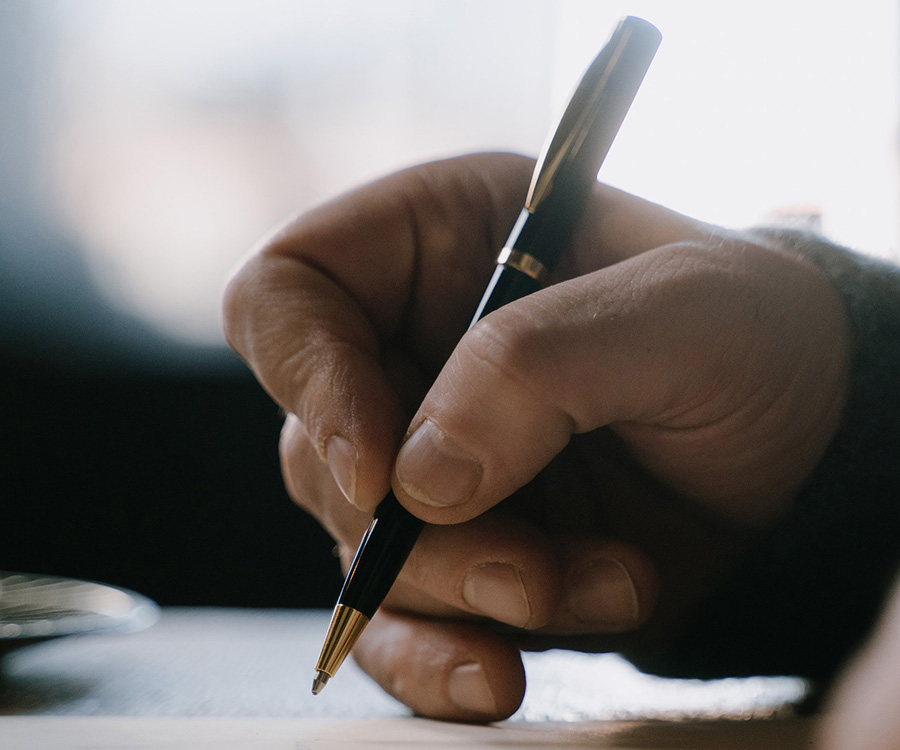 Close up of a hand writing a letter. Through the bars, correspondence with people in prisons matters!