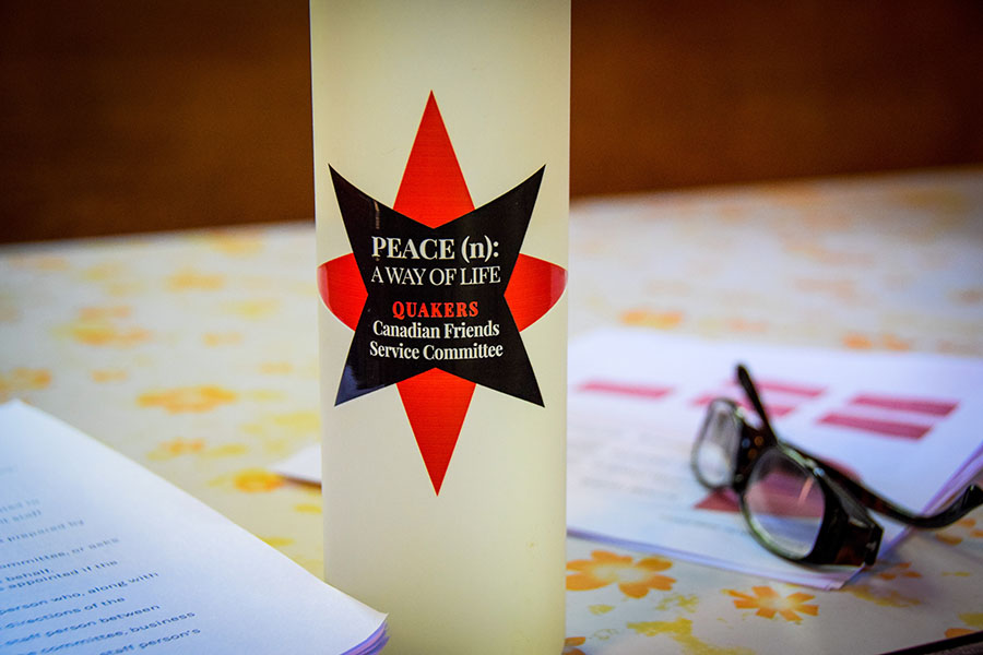 A desk with papers, a pair of glasses, and a water bottle with Canadian Friends Service Committee's logo and the text "Peace (n): A way of life"