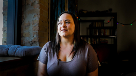 Lisa looks out of a window with a small smile. Every person is worthy of healing